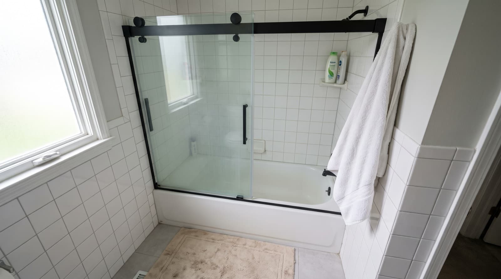 Sliding glass bypass shower door on a black top rail over a bathtub