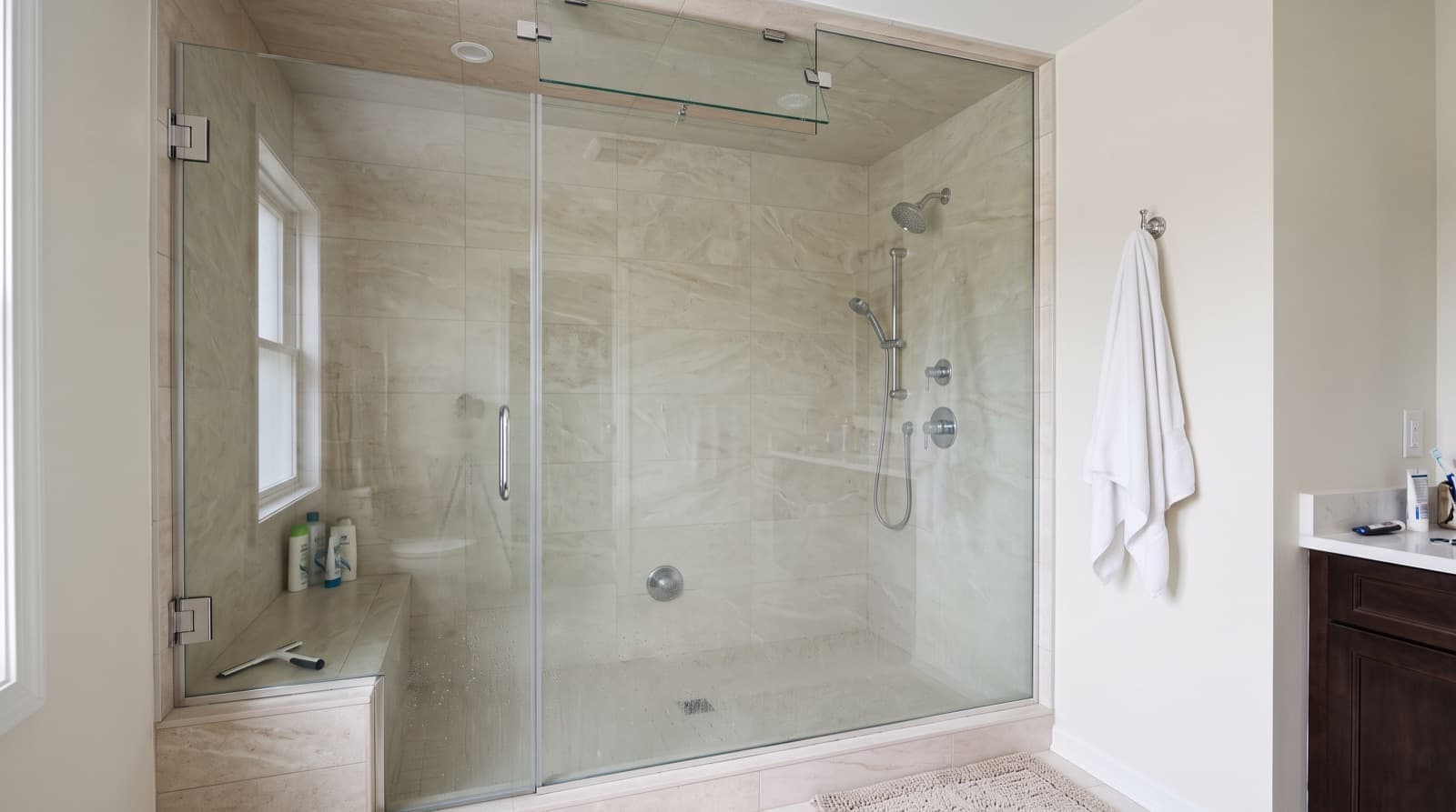 Steam shower enclosure with glass to the ceiling and a hinged transom panel tilted open