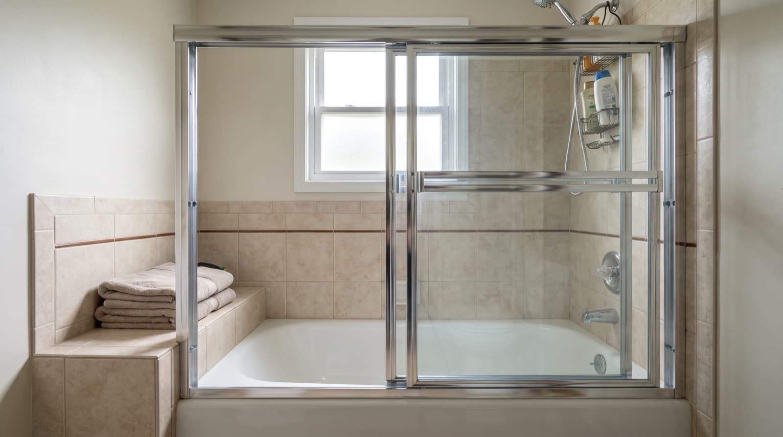 Framed sliding glass tub enclosure over an alcove bathtub with beige tile